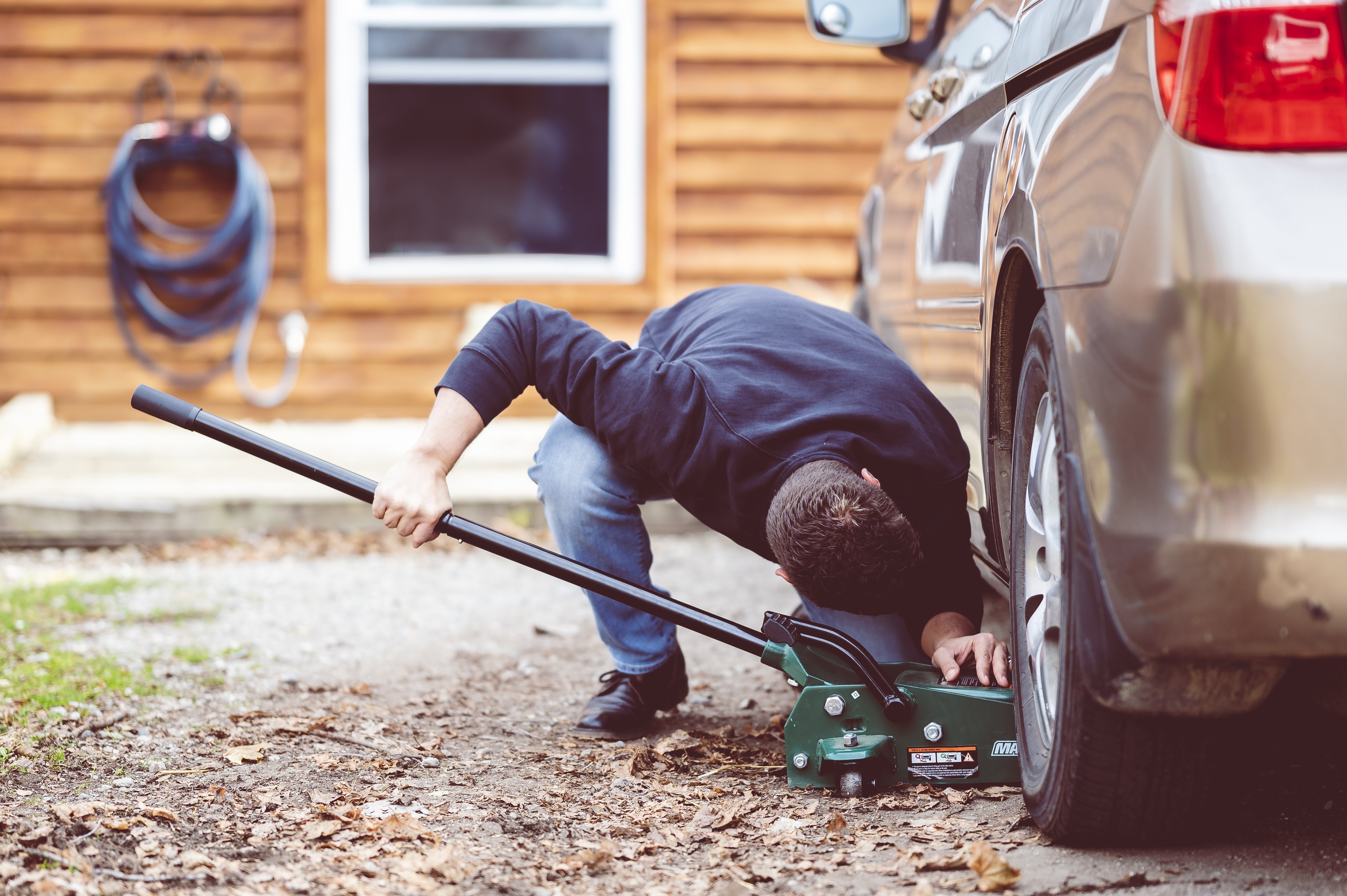 Person performing DIY car repair in a home garage, fixing vehicle engine and maintenance parts using hand tools, automotive maintenance, car servicing, mechanic work, vehicle repair.