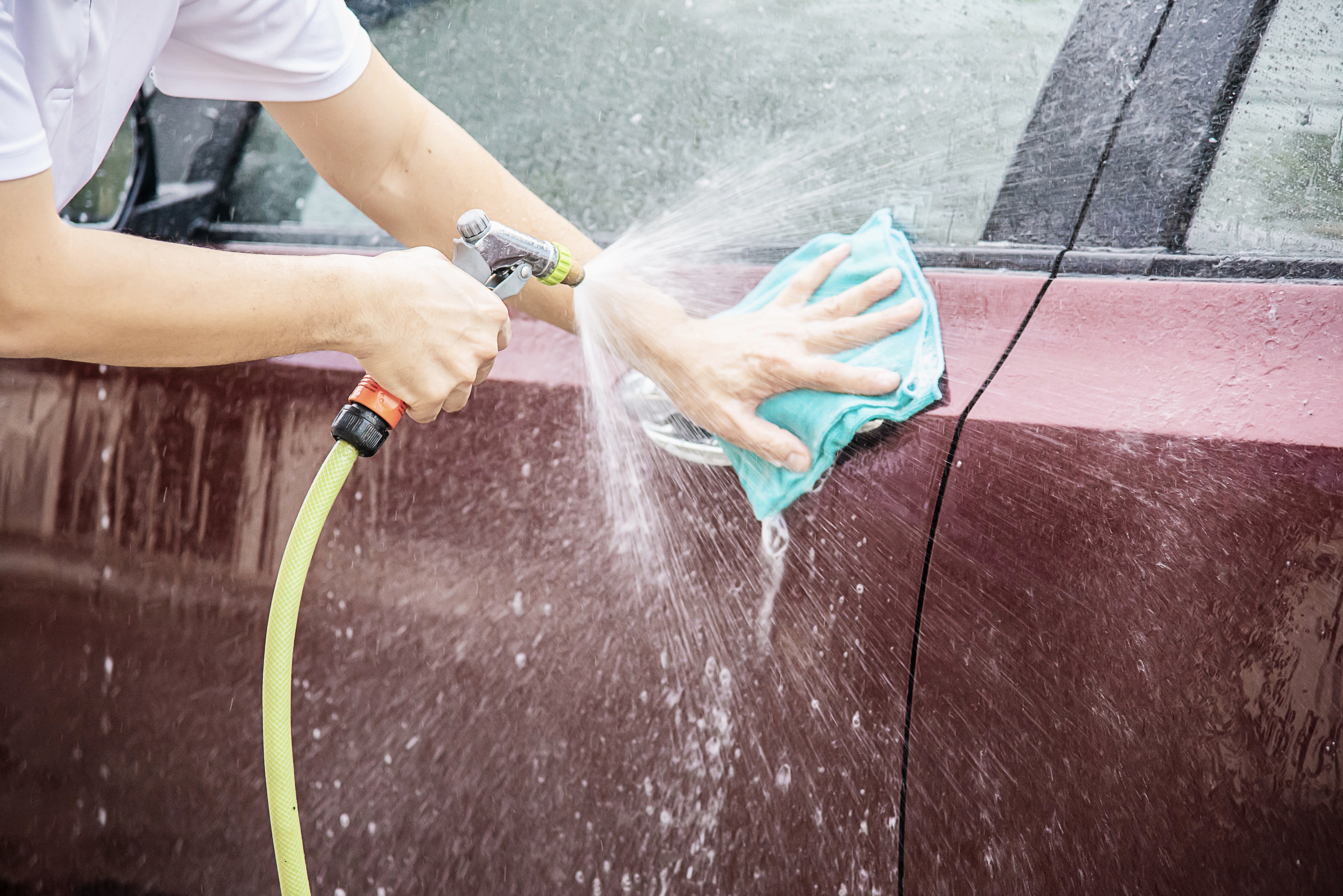 Hand washing a car with sponge and soapy water during spring cleaning