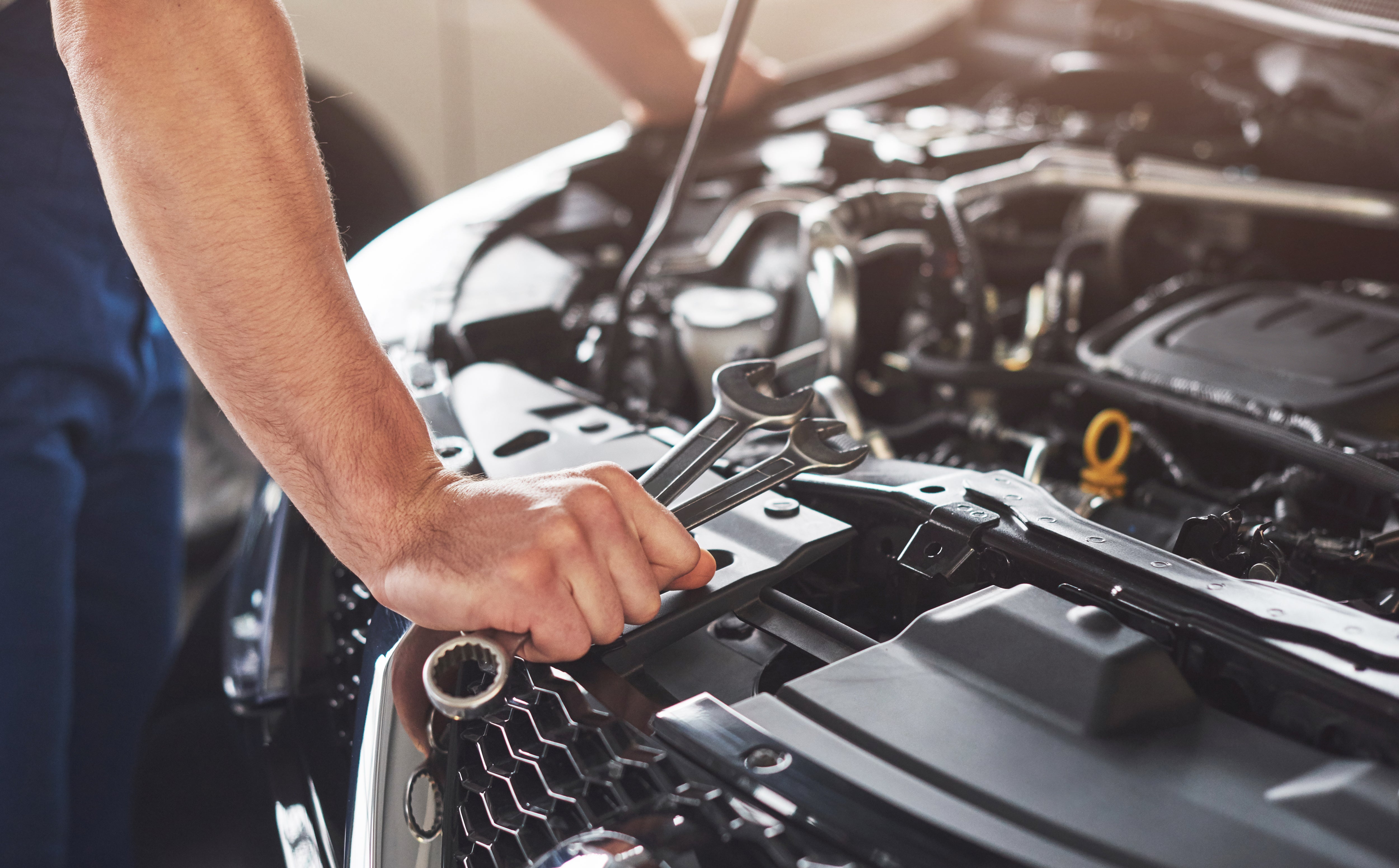 Person using a socket wrench to perform car maintenance on a vehicle in a garage diy vehicle maintenance